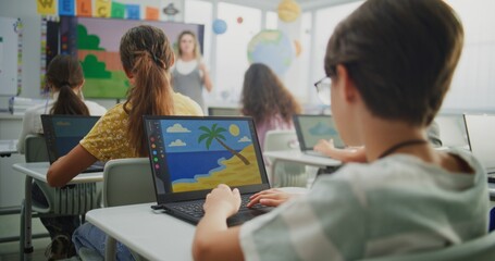 Female Teacher Guiding Young Kids During Art Lesson Using Digital Screen. Primary School Students Creating Digital Drawings on Laptops in Modern Classroom. STEM Learning for Creativity and Imagination