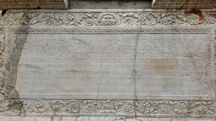 Herculaneum, Italy - 9 January 2025. At the Altar of Marcus Nonius Balbus, a Latin text is engraved in marble, bordered by carved vines and masks, commemorating his civic achievements.