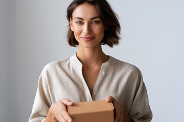 Obraz premium Smiling young caucasian female holding box in minimalist setting