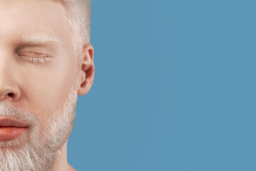 Bearded albino man posing with closed eyes against turquoise background, empty space. Guy with...