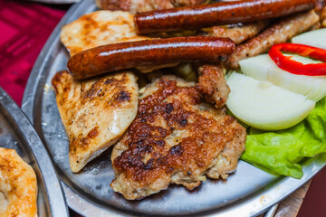 Mouth-watering close-up of a large platter filled with a variety of grilled meats, sausages, and golden French fries, perfect for a feast.