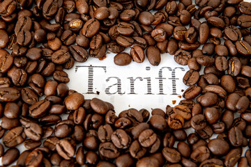 A heap of coffee beans surrounding the printed word tariff. A coffee tariff concept.