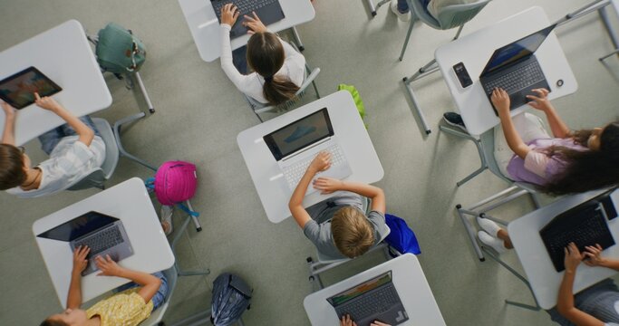 Primary School Students Working on Creative Projects on Laptops, Practicing Digital Skills in Art Class. Young Kids Drawing, Creating Pictures on Digital Devices. Interactive STEM Learning. Top View.
