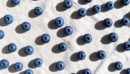 Overhead shot of blueberries arranged on a white linen surface.
