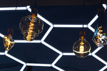 A decorative incandescent light bulb hangs from a dark ceiling.