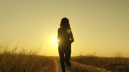 happy girl runs to meet her dream at sunset, doing sports jogging at dawn, listening to music in an active morning jog in rays of sun light, taking care of her health and being in shape, human figure.