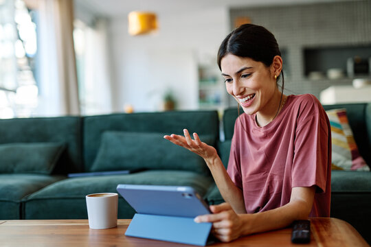 Portrait of a young woman  using tablet or laptop computer, having online meeting or browsing internet sitting on sofa couch at home