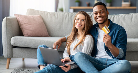 Easy Payments Concept. Portrait Of Cheerful Multicultural Couple With Laptop And Credit Card Posing...