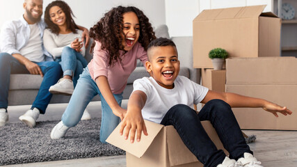 Fooling While Moving. Portrait of happy black family playing and celebrating relocation, laughing...