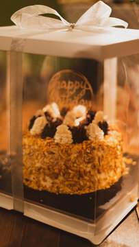 Classic Soviet "Polet" cake with nuts, whipped and chocolate cream, placed in a transparent gift box with ribbon bow. Festive birthday dessert, perfect as a celebratory present.