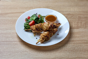 Grilled chicken skewers with salad and sauce
