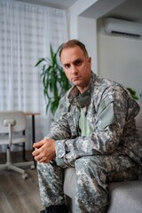 Soldier sitting on sofa looking sad at home