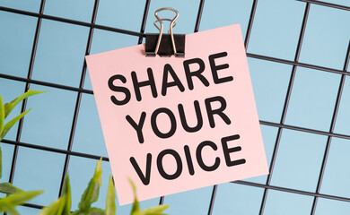 A pink sign that says Share Your Voice is hanging on a blue background