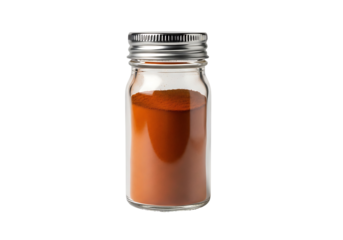 A clear glass spice jar filled with vibrant orange powder sits against a black background.