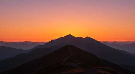 Naklejka premium Majestic mountain range at sunset with a vibrant orange sky and silhouetted peaks