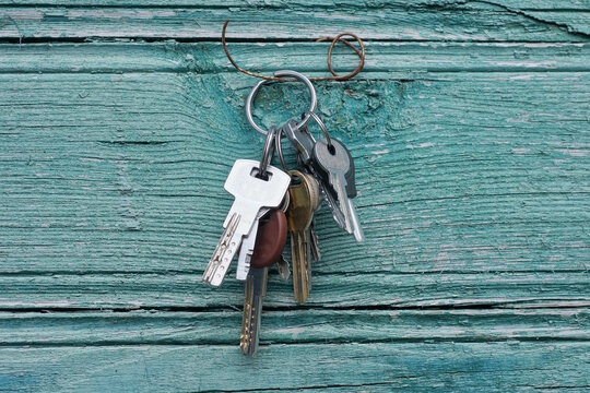set metal door keys on iron ring hanging on green wooden wall