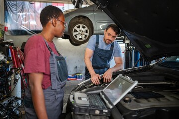 Mechanics using diagnostic software checking car engine in auto repair shop