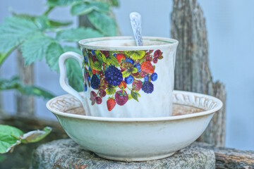 one white ceramic cup with colorful pattern on a plate stands on gray post in the street