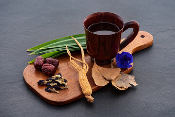 Brain-nourishing tea recipe to restore memory and reduce stress with chinese jujube and ginseng herbs isolated on black ceramic background.