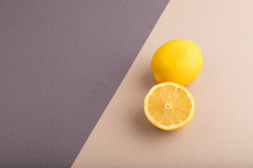 Yellow Lemon Cut in half on beige and gray pastel paper, Side view, copy space
