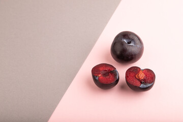 Purple Plum Cut in half pink and gray pastel paper, Side view, copy space