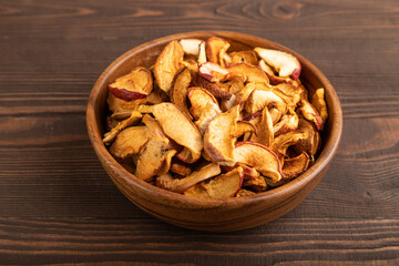Dried Apples in wooden bowl on brown wooden. Side view, close up