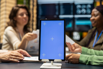 Diverse associates setting objectives with copy space display on tablet, empowering women creating projects through visuals, data driven planning and corporate innovation for growth.