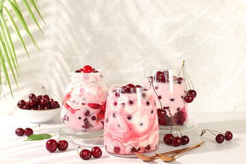 Fruit yogurt with cherries and fresh cow cream for healthy nutrition in a glass on an elegant table. Healthy breakfast with ingredients, kitchen background. Natural food and detox diet concept