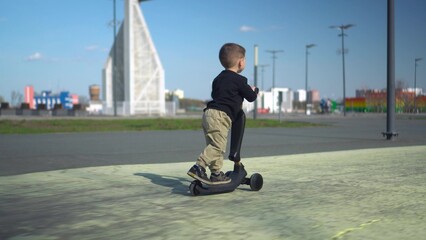 A Young Child is Joyfully Riding a Scooter in a Beautiful Sunny Park on a Lovely Day