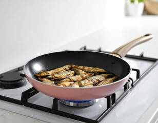 Sizzling Small Fish in a Rose Gold Pan on a Modern White Gas Stove.