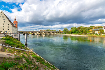 Obraz premium The old stone Steinerne Brücke bridge over the Danube River connecting the medieval Altstadt old wotn with Stadtamhof island in the Bavarian city of Regensburg, Germany.
