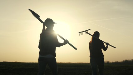 Farmer girls walk across the field to work with a shovel and rake at sunset in the sky, young and adult women are going to grab the earth, business on growing plants in the countryside outdoors, life © TO LOVE