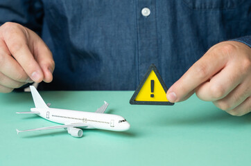 A man holds a sign of attention near a passenger plane. Some problems or malfunctions that risk...