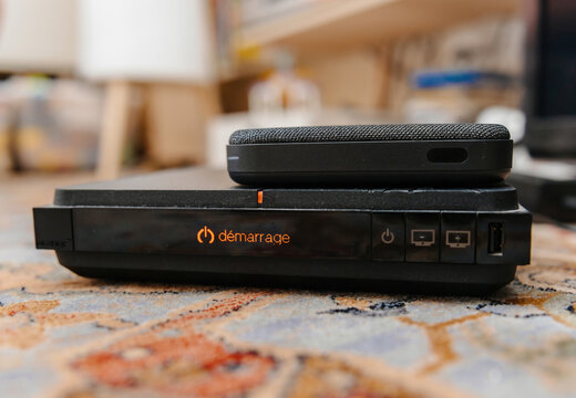 Paris, France - Feb 17, 2025: An old Livebox TV decoder from Orange dating back to 2017 sits on a colorful carpet with a modern 2025 generation Livebox on top, showing a contrast in size and design.