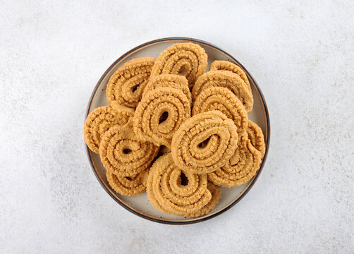 Indian chakli (murukku) snacks on white background. Top view. Traditional crispy spiral Diwali snack.