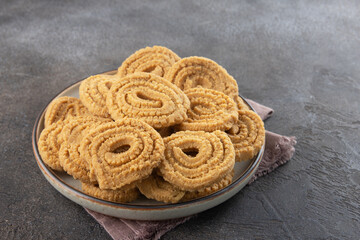 Indian chakli (murukku) snacks on gray background. Traditional crispy spiral Diwali snack.