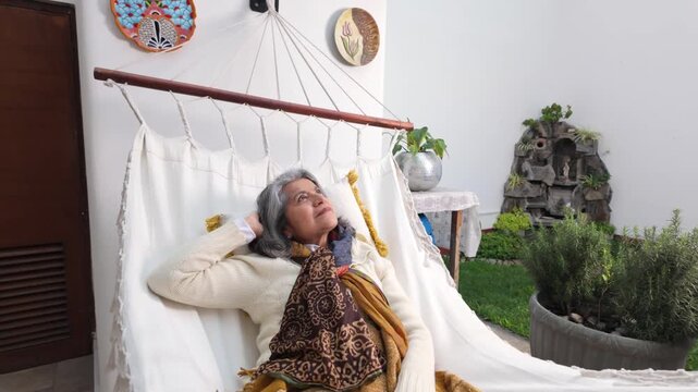 Senior woman relaxing in hammock at home in slow motion