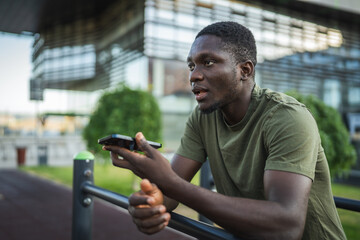 Young man sending a vocal message on his smart phone in the city