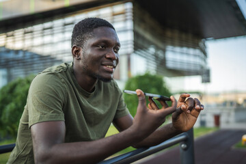 Young man sending a vocal message on his smart phone in the city