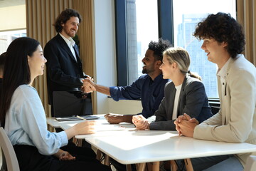 Diverse Team Working Together in Modern Co-Working Space. Casual meeting of smiling diverse business team analyzing financial data. Multiethnic business people working together in the office.