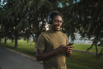 Obraz premium Young man wearing headphones listening to music on smart phone in park