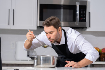 modern chef in professional uniform. close-up on the hand of male chef who is stirring soup in pot...