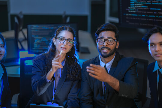 A diverse team of AI developers presents a project update during a video conference. A female lead points at the screen, explaining the architecture of a new generative AI model. - Powered by Adobe