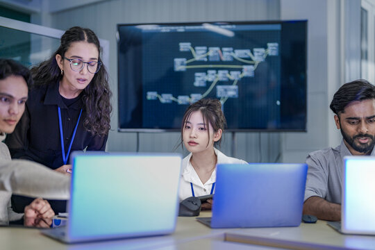A cybersecurity incident response team analyzes a live threat in a Security Operations Center (SOC). A female lead directs her team as they trace the attack vector on a network map.