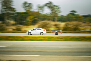 Momentum & Craft: White Sedan Towing Wooden Trailer