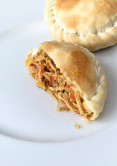 Empanadas de pollo con guiso jugoso y mucho relleno, partida o picada por la mitad. 