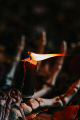 Burning Candle on Skeleton Hand with Autumn Leaves.Spooky Halloween Candlestick.Skeleton Hand...