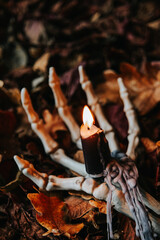 Spooky Halloween Candlestick.Skeleton Hand Holding Candle in Autumn Leaves.halloween candle.Burning...