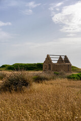 Obraz premium Old ruined abandoned house surrounded by dry grass in a desolate landscape in Sardinia, Italy, evokes a sense of decay and abandonment