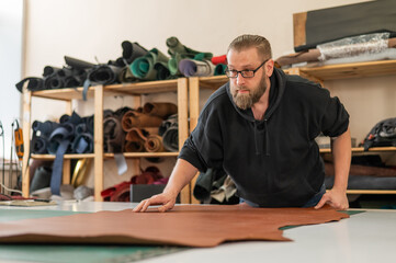 Caucasian bearded man working as a tanner in a workshop. 